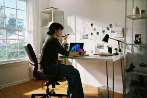 Person working at desk with laptop and phone.